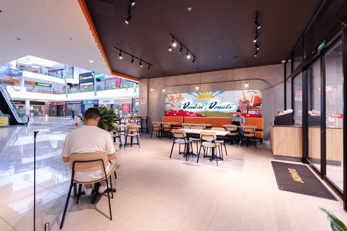 Dunkin Donuts - Open plan mall kiosk design with varied seating options and brand graphics - Contract Workplaces.webp